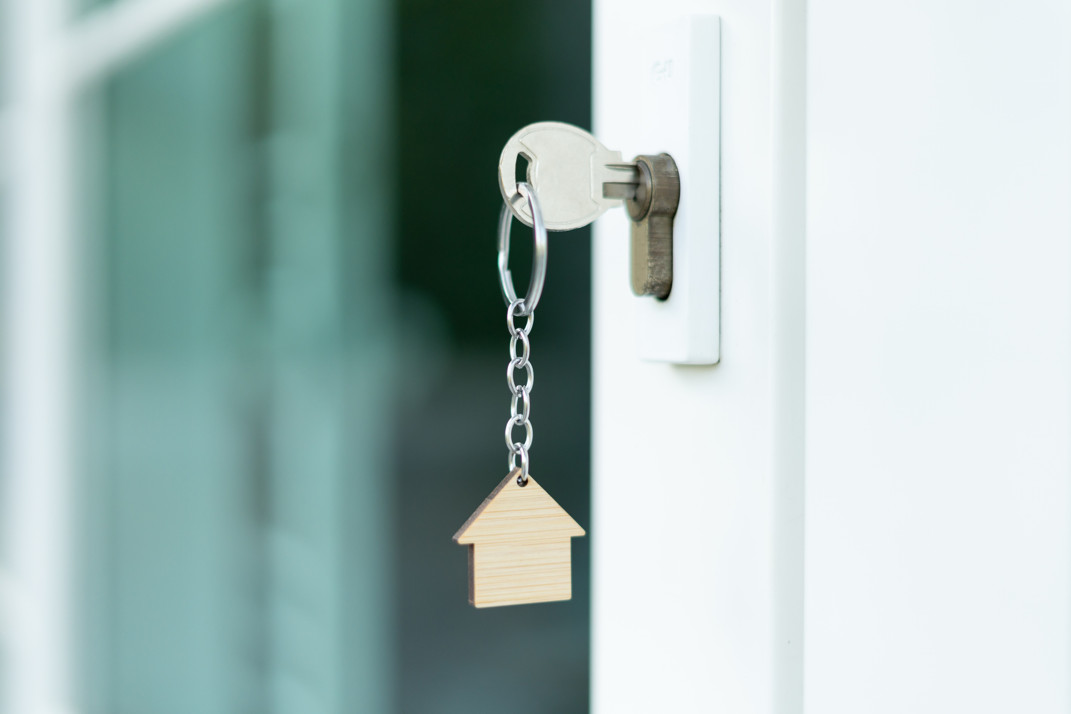 Llave en una puerta con llavero con forma de casa.