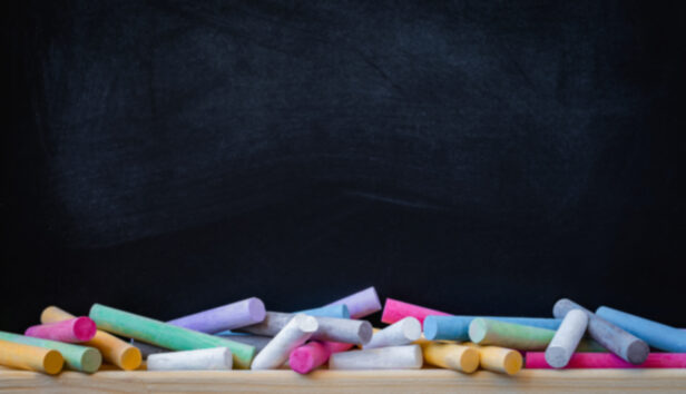 Tizas de colores delante de una pizarra