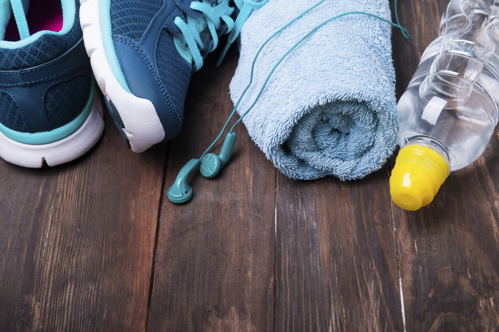 Primer pla de sabatilles d'esport, auriculars, tovallola i ampolla aigua