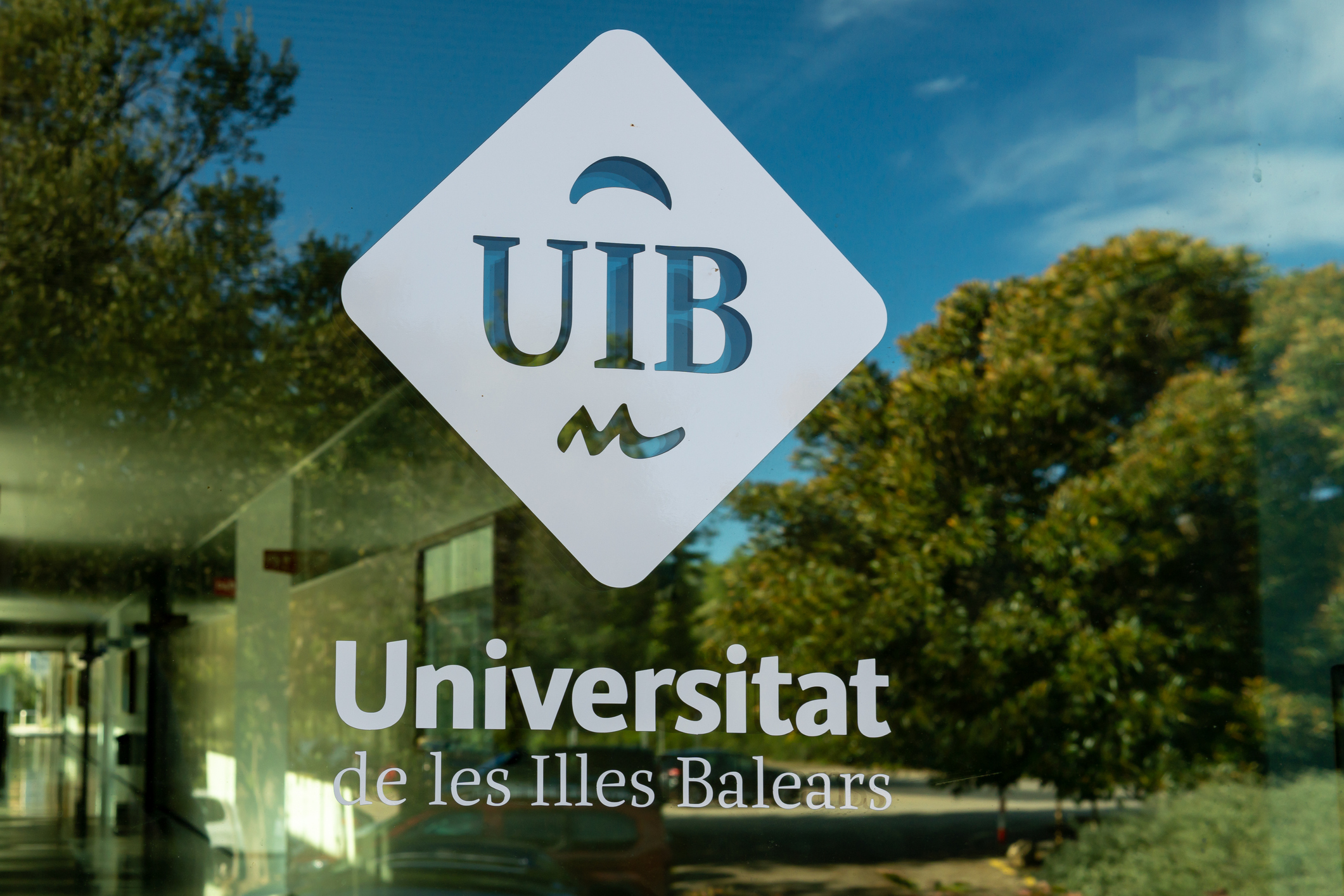 Impressió del logotip de la Universitat de les Illes Balears al vidre d'un edifici del campus