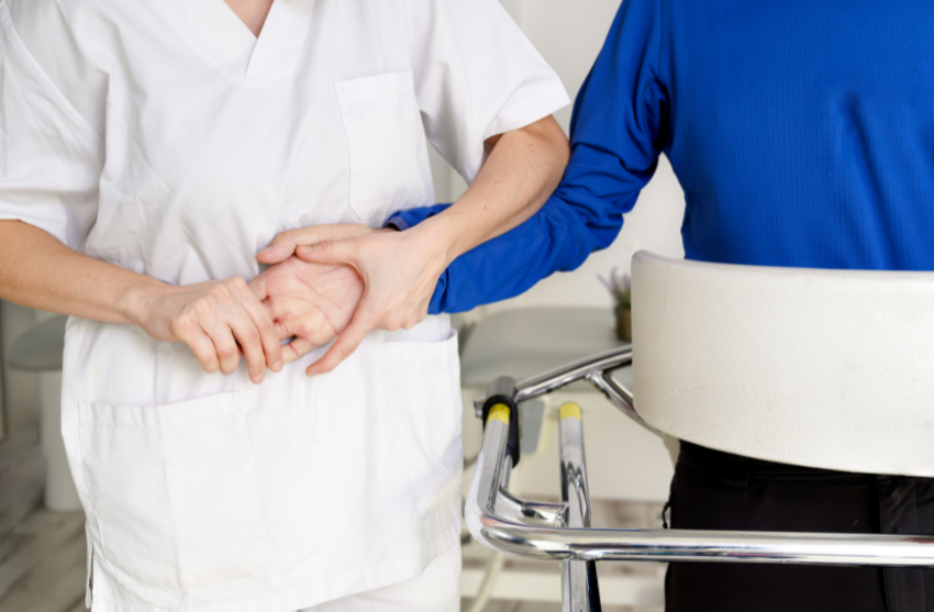 Una professional sanitària agafa la mà d'un pacient en rehabilitació.