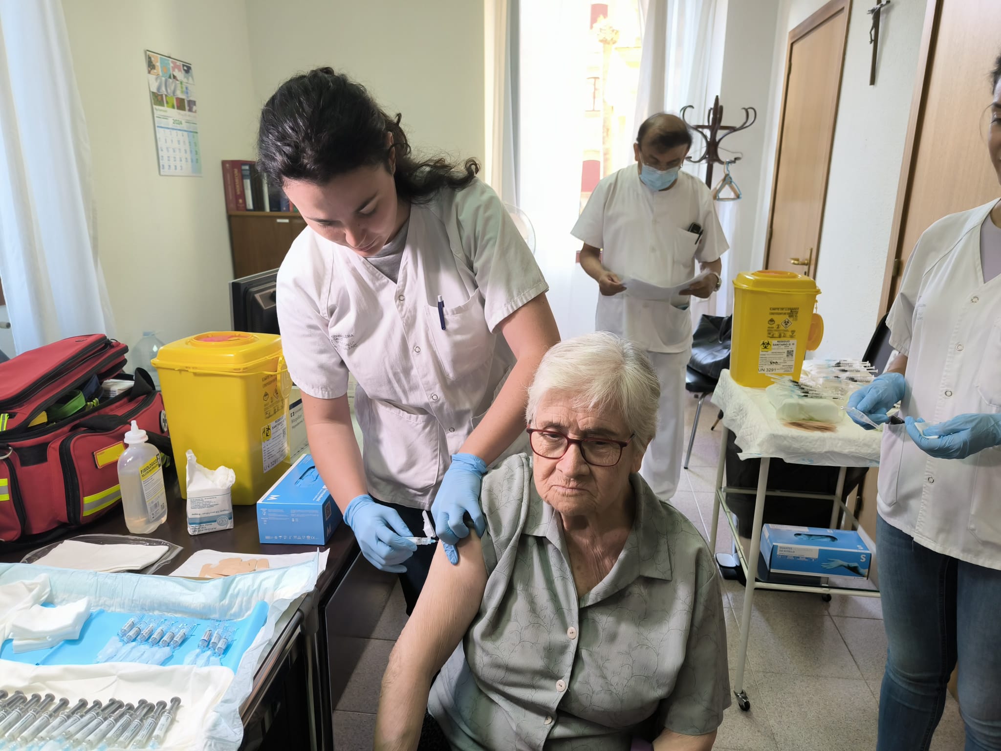 Una infermera posa una vacuna a una dona gran.