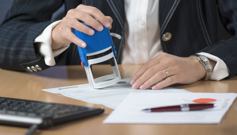 Les mans d'una dona que segella i certifica un document.