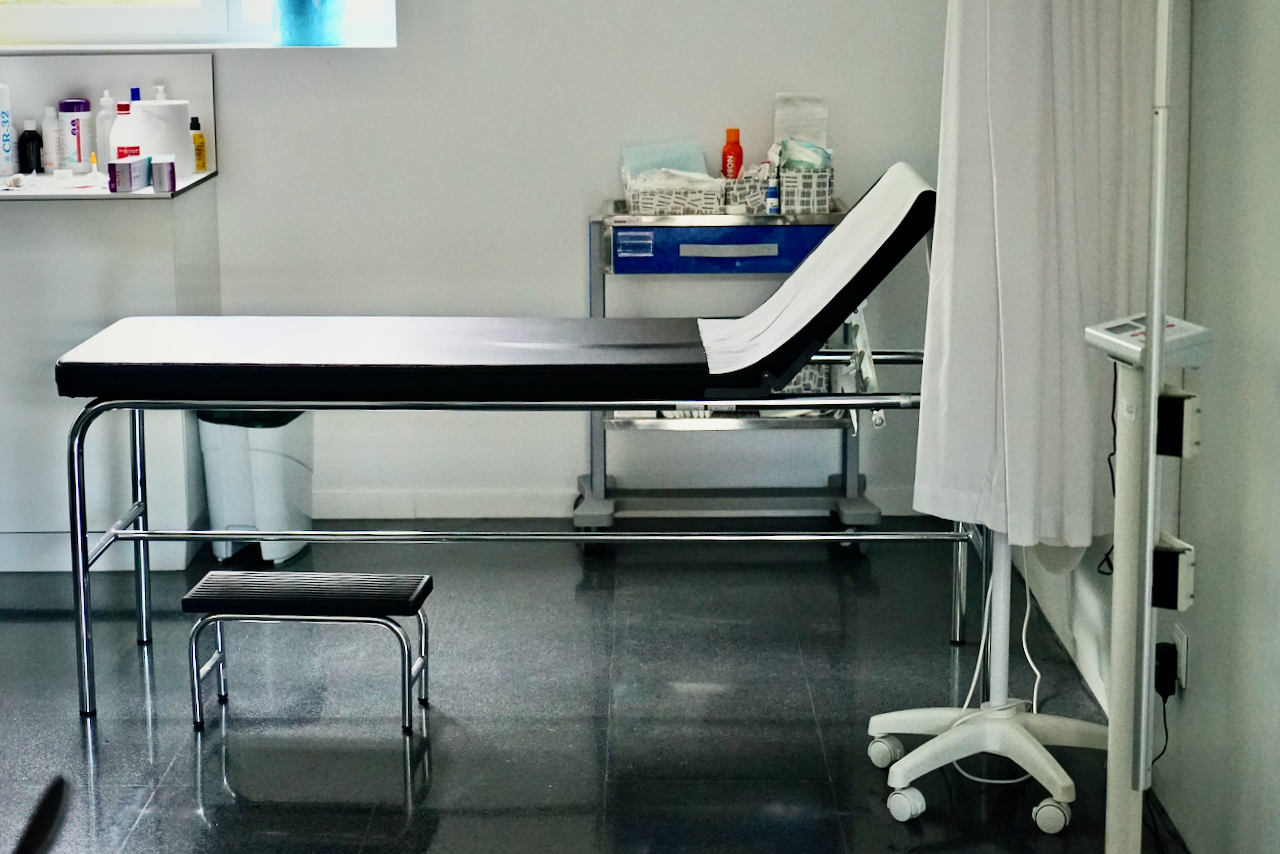 Sala d’exploració mèdica amb una llitera i material sanitari al fons.