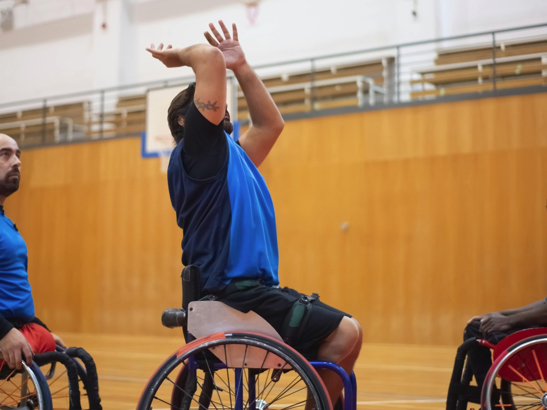 Home en una cadira de rodes jugant a bàsquet.