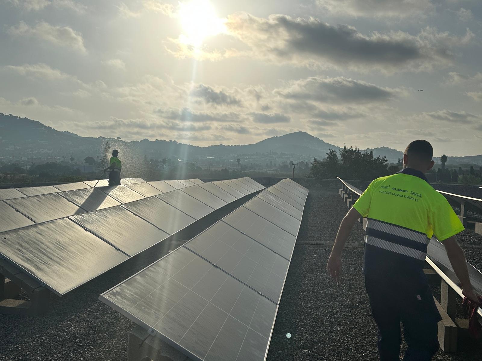 Dos operaris treballen al costat d'uns panells fotovoltaics.