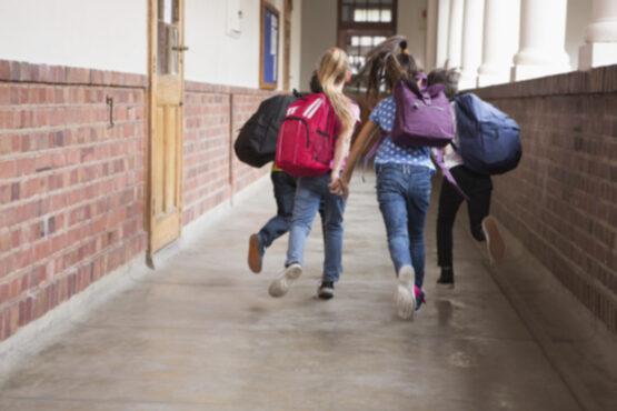 Niñas con mochila corriendo por un pasillo 